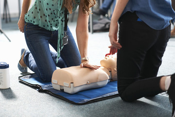 College student performing CPR on mannequin in class