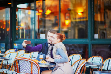 Romantic couple taking selfie in cafe in Paris, France