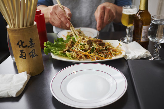 View of person tucking into plate of noodles