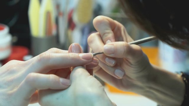 A female master makes manicure of hands girl