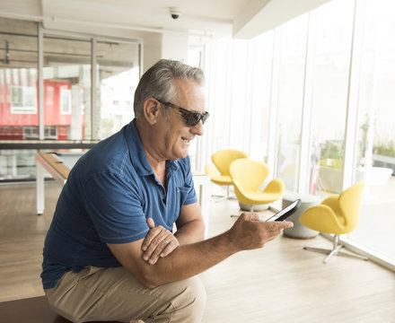 Senior man wearing sunglasses reading smartphone text