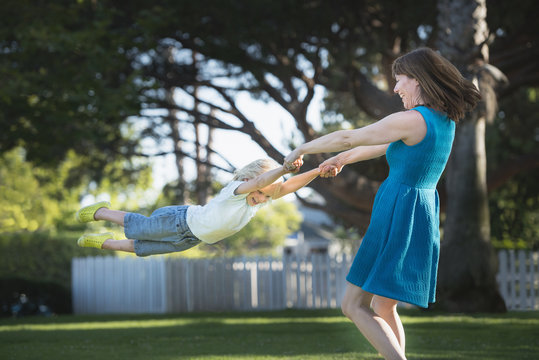 Mother swinging son around, outdoors