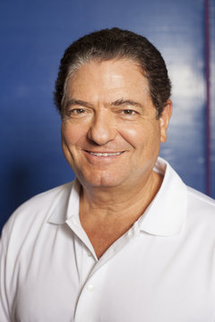 Portrait of senior man (table tennis player) wearing white polo shirt looking at camera smiling