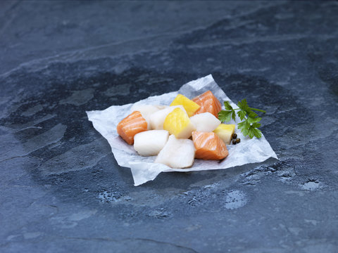 High angle view of raw cubed salmon, cod and herbs for making fish pie