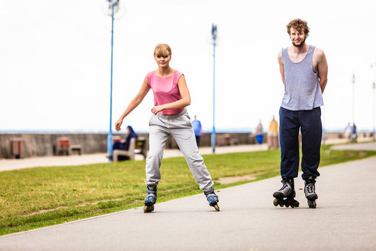 Friends rollerblading together have fun in park.
