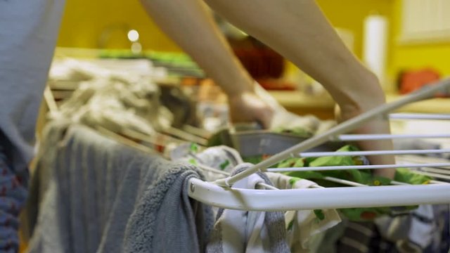 Male standing in kitchen hanging clothes on dryer rack after doing his laundry.
