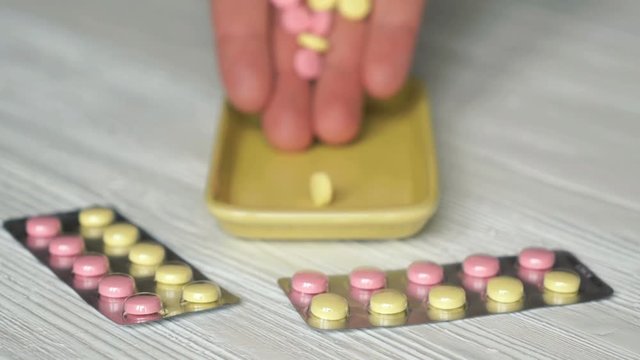 Hand folds pills in container placed on the table