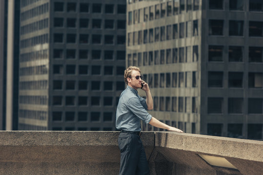 Businessman talking on smartphone from rooftop, Los Angeles, USA