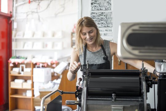 Woman working on letterpress print machine in workshop