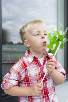 Boy blowing pinwheel on patio