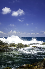 soft wave hitting the rock at the shoreline with cloudy and blue sky background