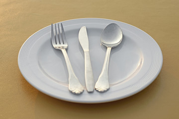 spoon fork and knife on empty white plate