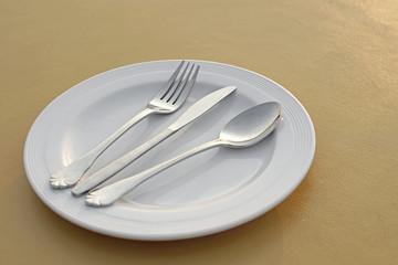 spoon fork and knife on empty white plate