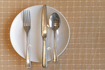 spoon fork and knife on empty white plate