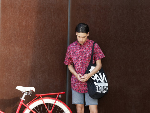 Young man standing beside bicycle