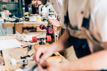 Young men in carpentry workshop looking down making skateboards
