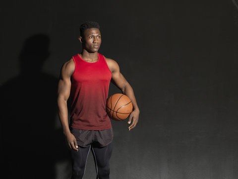 Portrait of basketball player with ball, black background