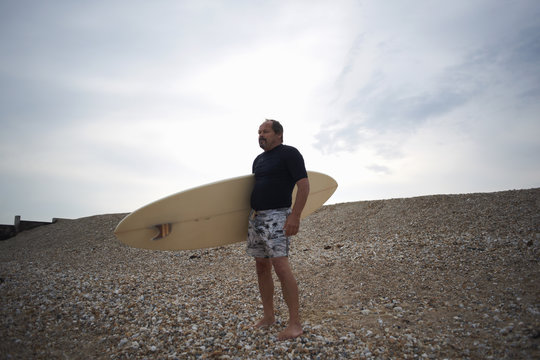 Surfer carrying surfboard on beach