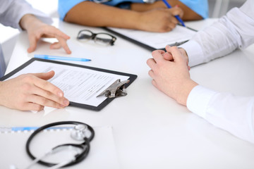 Two doctors and male patient discussing medical history at the table, close up