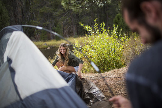 Young couple putting up tent on riverside, Lake Tahoe, Nevada, USA
