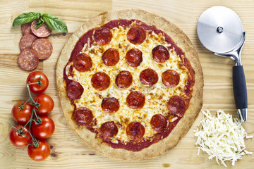 pizza with cutter, tomatoes and slices of ham