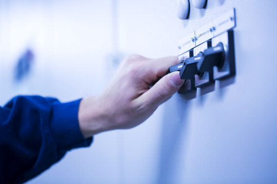 Cropped view of young mans hand adjusting dial on switchgear