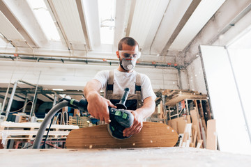 Man sanding skateboard in workshop
