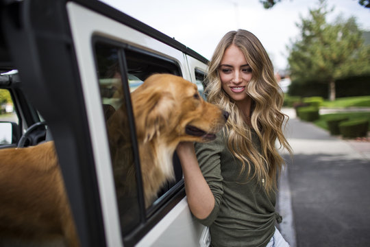Young woman petting her dog at jeep window