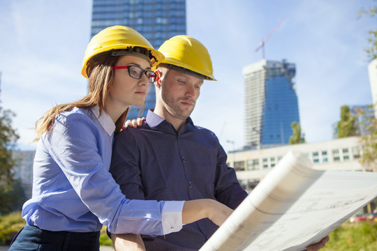 Building contractors wearing hard hats looking at blueprint