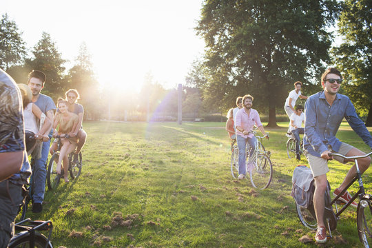 Rows of party going adults arriving in park on bicycles at sunset