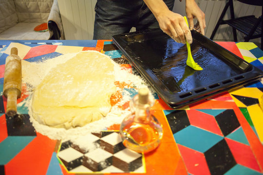 Womans hands oiling baking tray on kitchen table