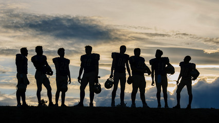 Silhouette of group of young american football players, standing in row