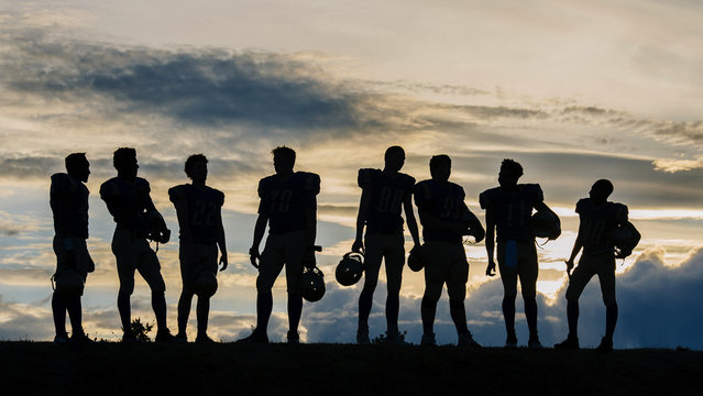 Silhouette of group of young american football players, standing in row - Powered by Adobe