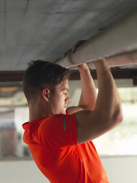 Young man doing pull ups under bridge