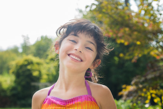 Low angle portrait of girl wearing colourful halter top looking at camera smiling