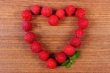 Heart of fresh raspberries on wooden table, symbol of love