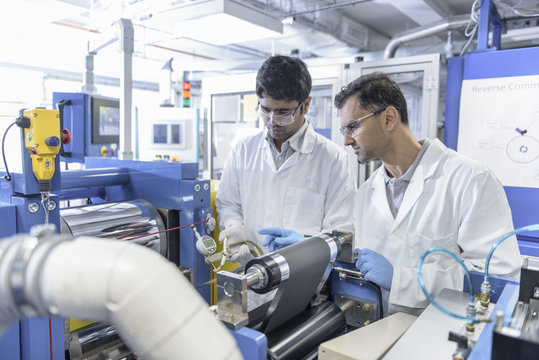 Scientists with lithium ion battery production line in battery research facility