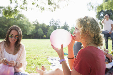 Young woman blowing up balloon at park party