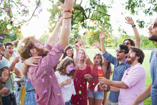 Adult crowd celebrating with arms raised at sunset party in park