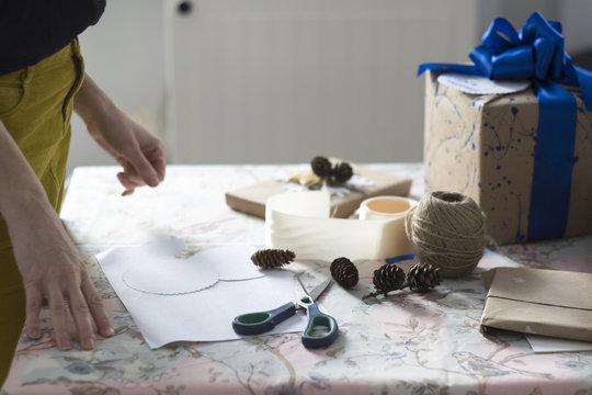 Side view of mid adult woman wrapping gift at table