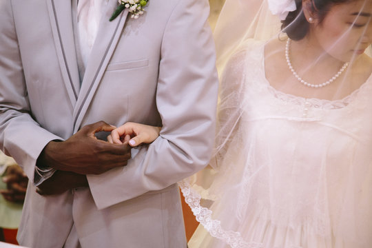 Cropped view of bride wearing veil and bridegroom holding hands
