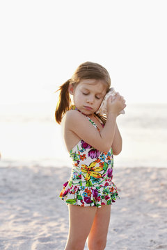 Portrait of girl listening to seashell at beach