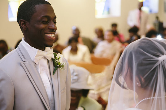 Bridegroom in church wedding ceremony smiling at bride
