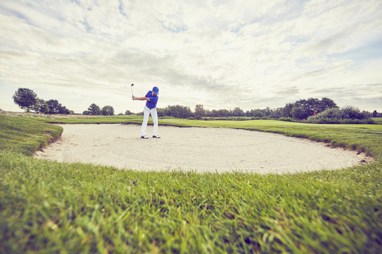 Golfer hitting ball in sand trap, Korschenbroich, Dusseldorf, Germany