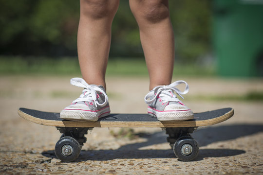 Legs of girl wearing canvas shoes standing on skateboard