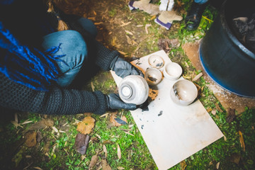 High angle view of young woman quality checking clay pots removed from fire