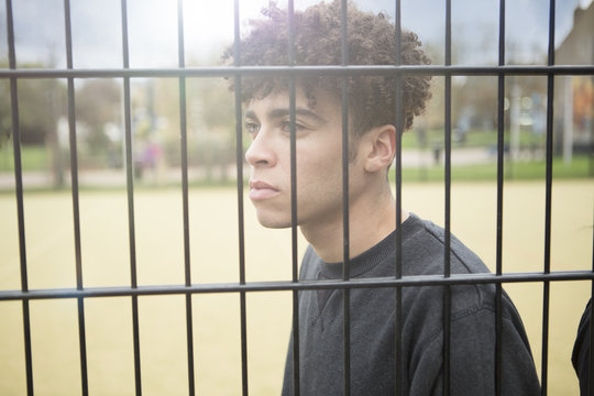 Young man leaning against fence