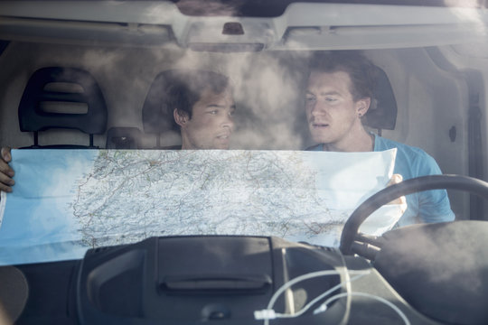 View through windscreen of young men in recreational van looking at map,Sardinia, Italy