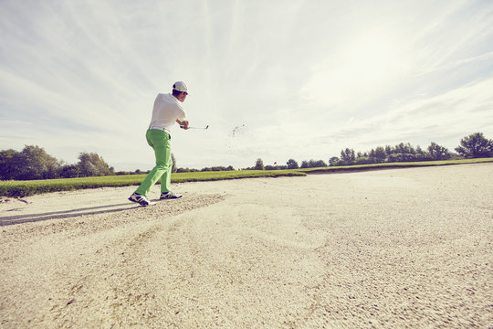 Golfer hitting ball in sand trap, Korschenbroich, Dusseldorf, Germany