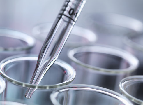 Close up of graduated pipette pipetting liquid into test tube